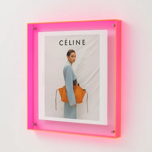 Roze acryl foto frame met modeposter aan de muur.